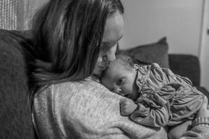 An intimate black and white portrait of parent and baby sharing a quiet moment.