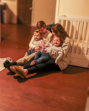 A family shares laughter while sitting together on a red floor.