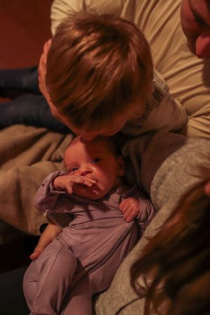 A gentle interaction between siblings in warm, ambient lighting.