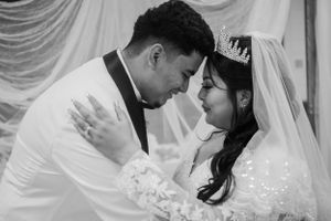 A romantic black and white photo of newlyweds embracing during their wedding ceremony.
