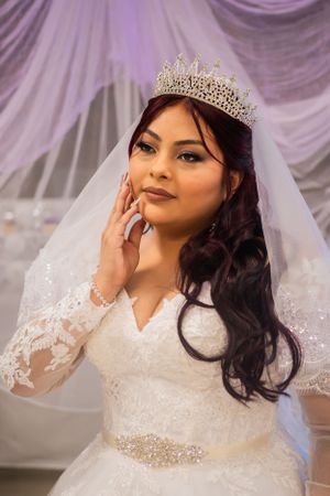 Close-up portrait of bride wearing crystal crown and lace wedding dress with sparkly belt.