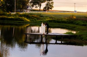 Silhouetted couple on a dock with golden sunset reflections in the water.