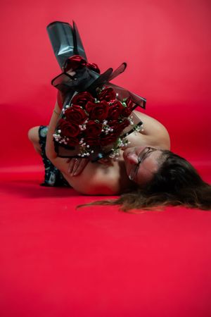 Person in boots posing with red roses against bright red background.