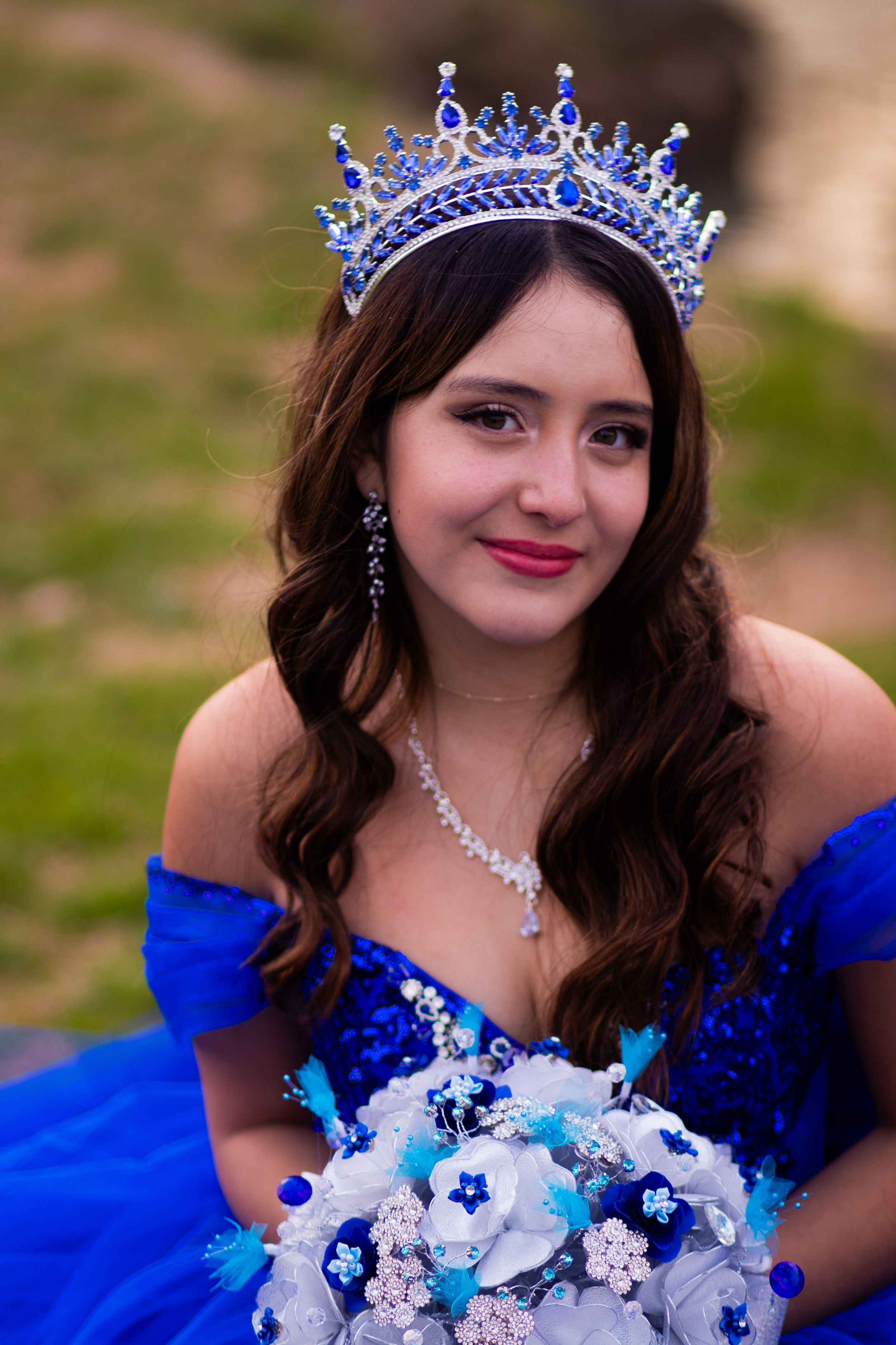 A stunning royal blue quinceañera dress with matching crown and bouquet creates an elegant portrait.