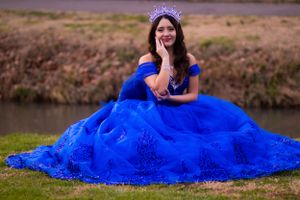 A stunning royal blue ball gown with intricate details photographed near a pond.