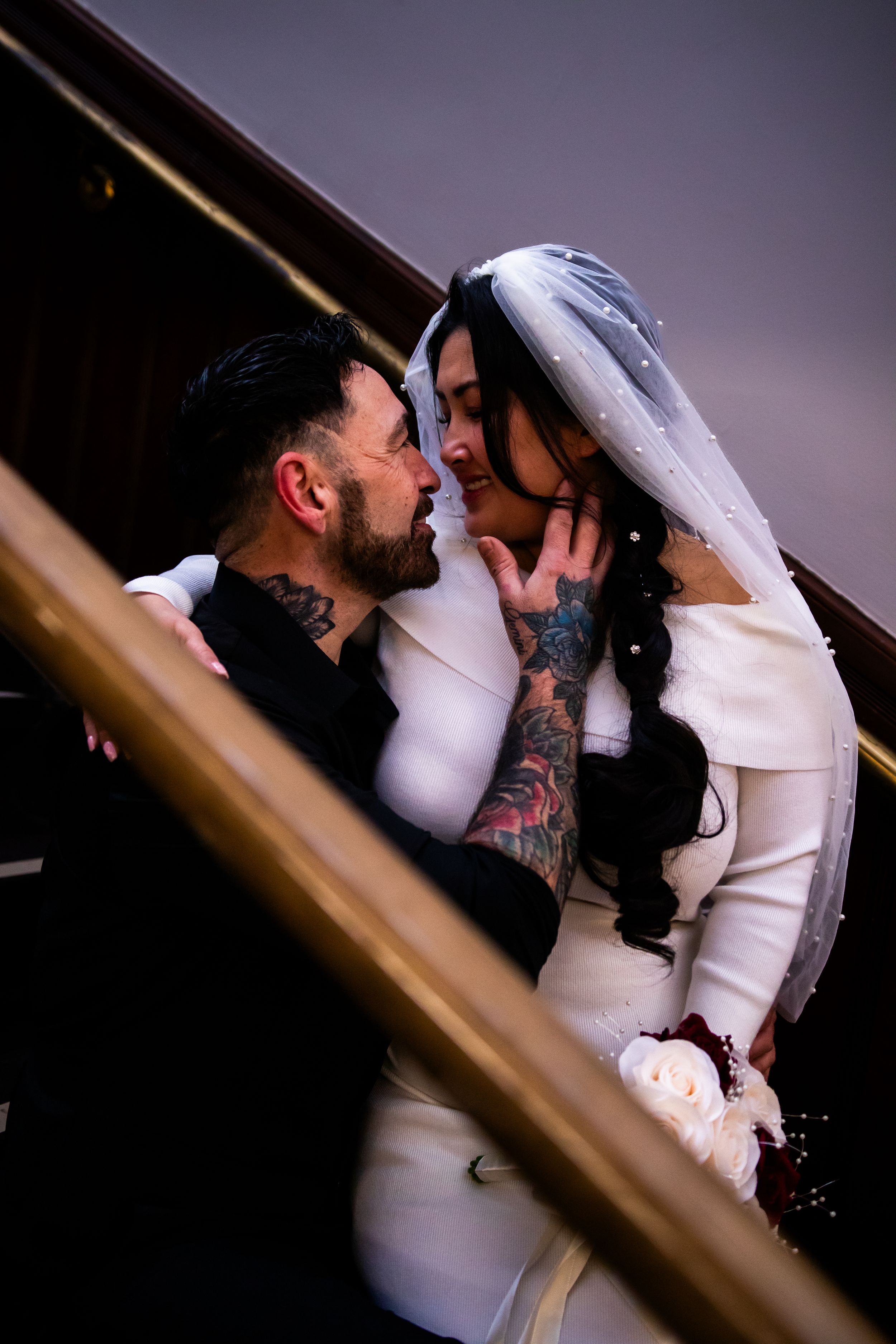 Intimate moment between newlyweds on wooden stairs.