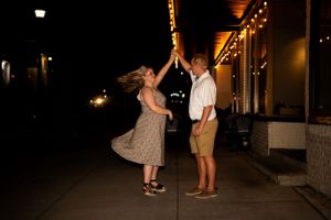 A couple dances together under glowing lights outside a building at night.