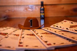 A brown cowboy hat with number 1 displayed with playing cards on wooden table.