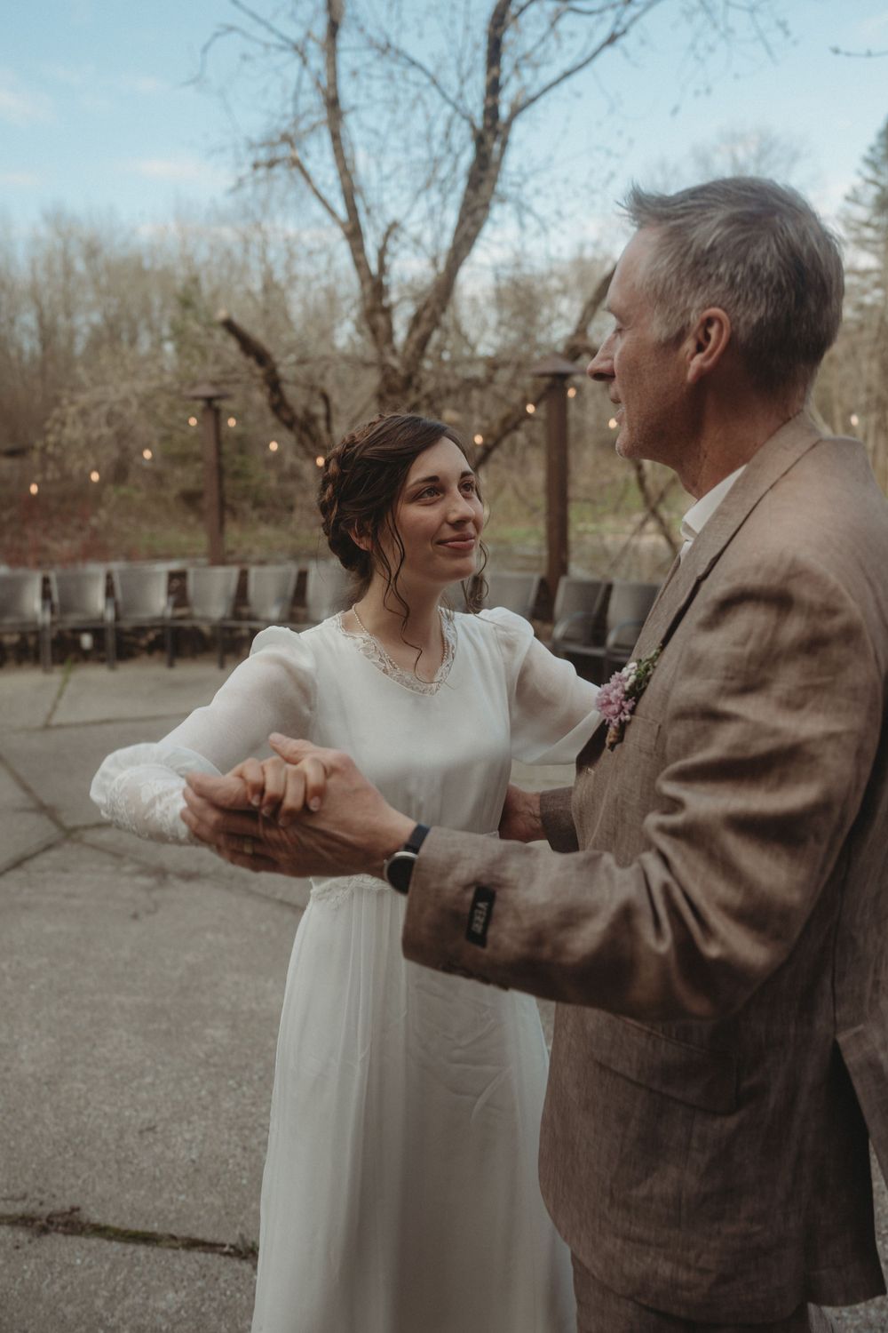 A couple shares an intimate dance moment outdoors with string lights in the background.