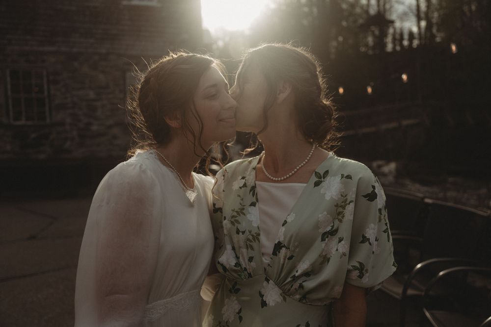 Two people share an intimate moment at sunset with soft backlighting creating a romantic atmosphere.