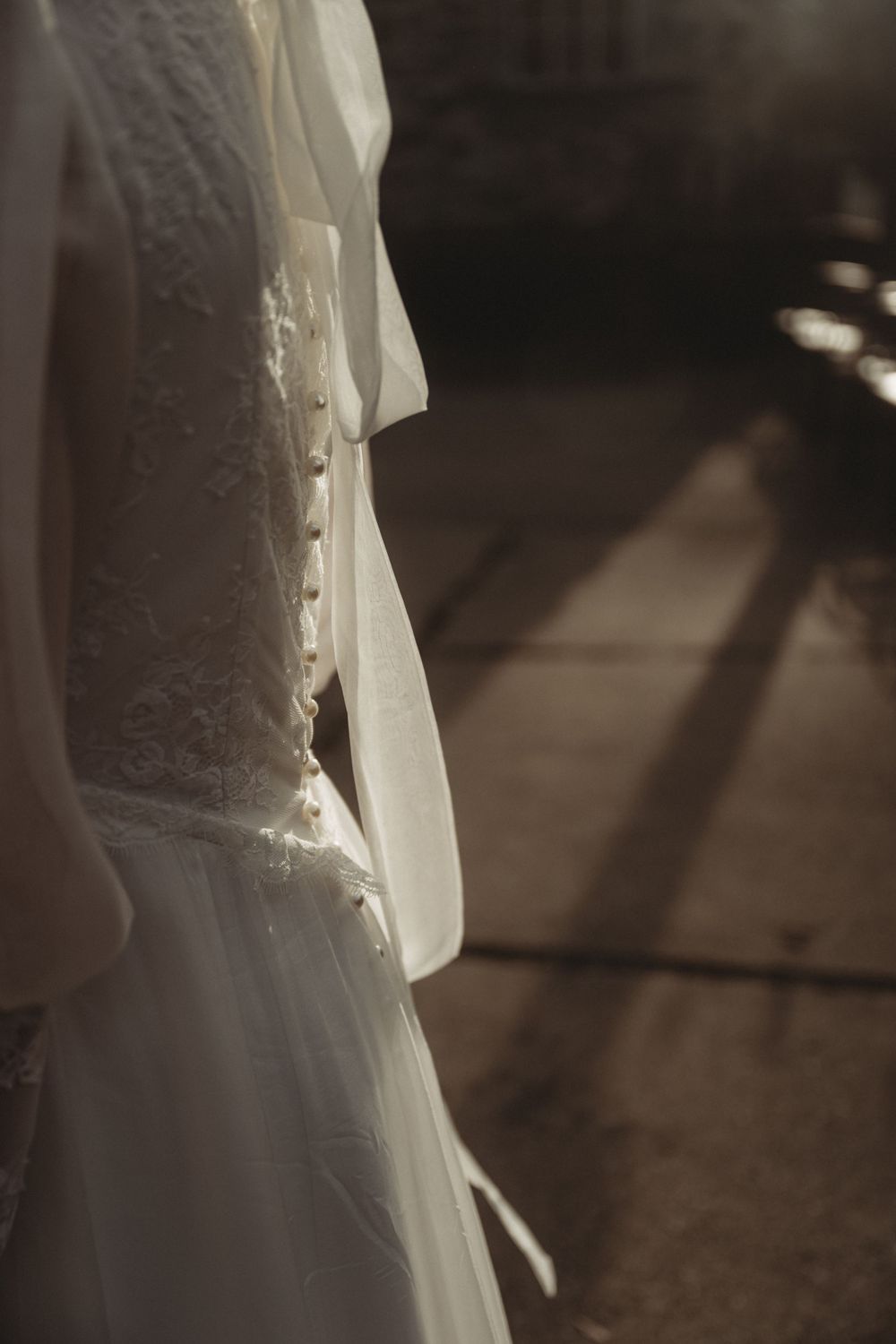 Close-up detail shot of white wedding dress lace and fabric in dramatic lighting.