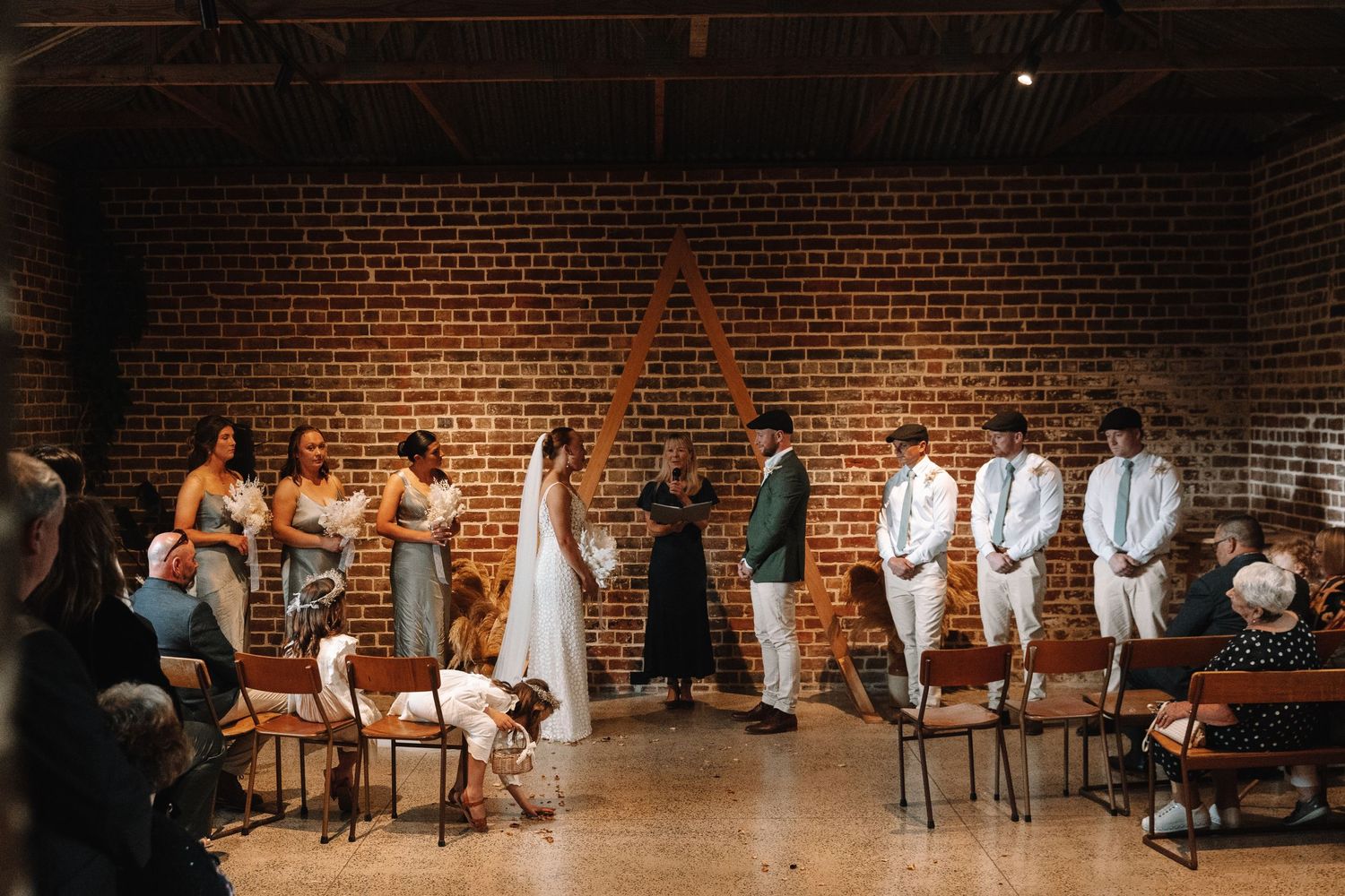 Intimate wedding ceremony taking place in an industrial brick-walled venue.