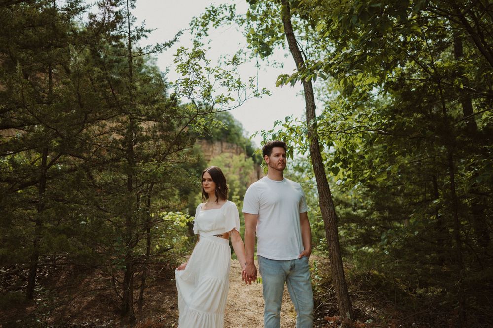 Two people walk together on a wooded path during a summer photoshoot.