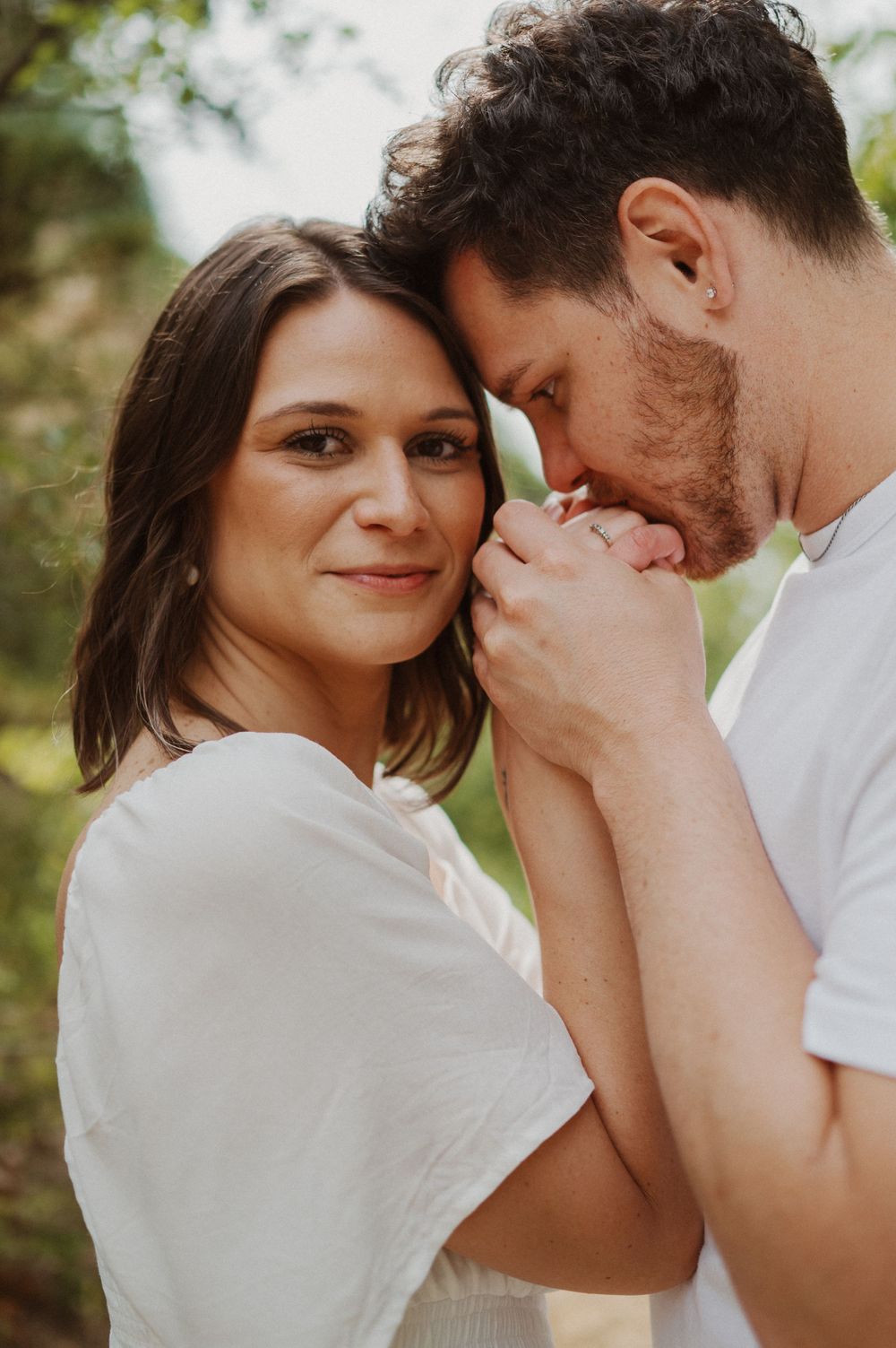 Close-up shots of a couple sharing tender moments while wearing coordinated white outfits.