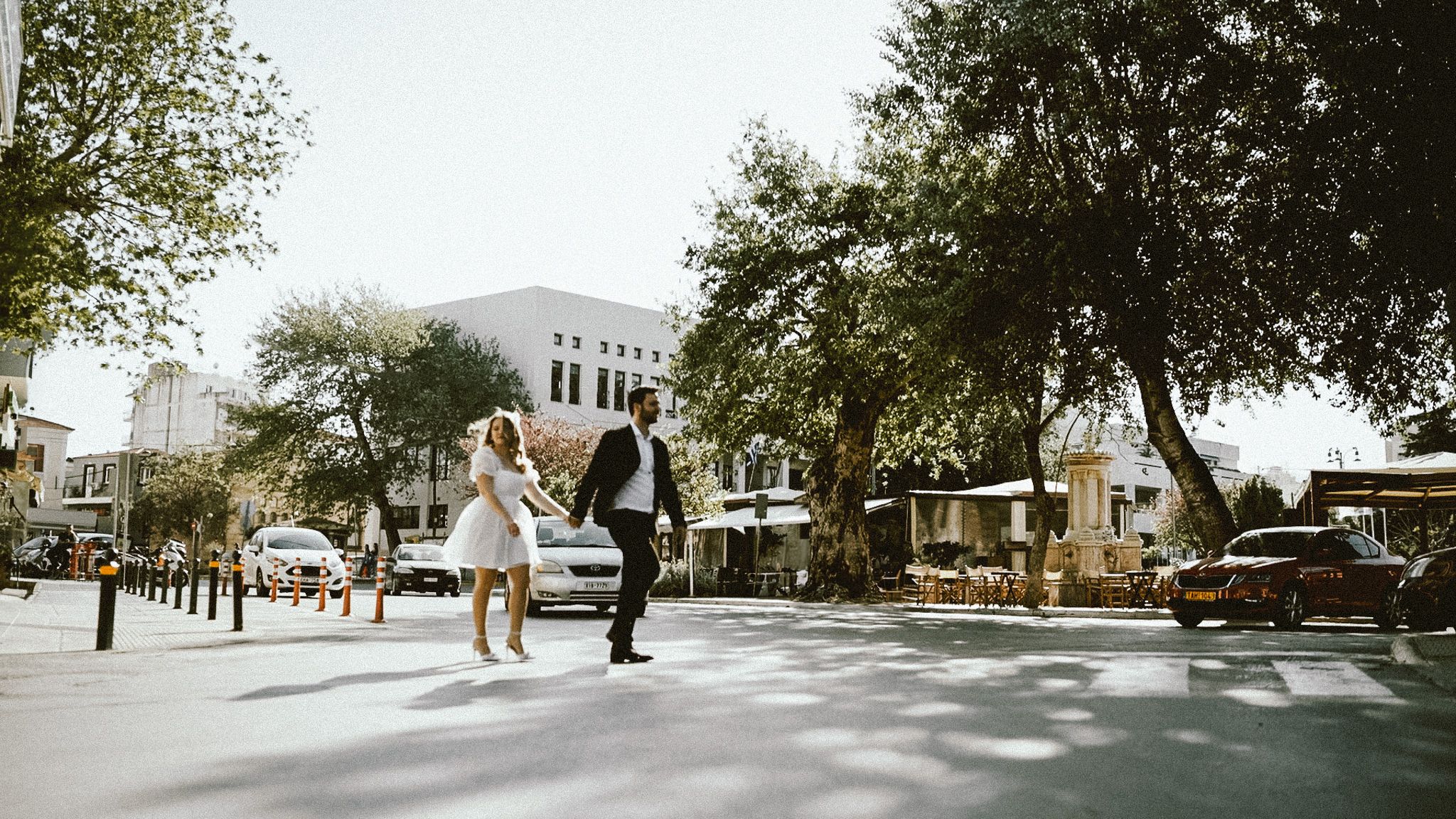 A joyful couple running together on a tree-lined street.
