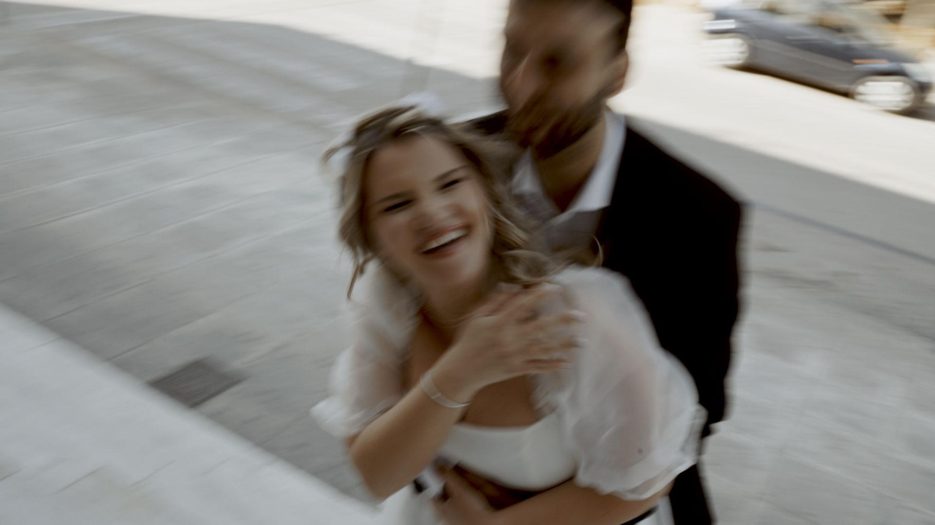 A joyful wedding couple sharing a playful moment on white stone steps.