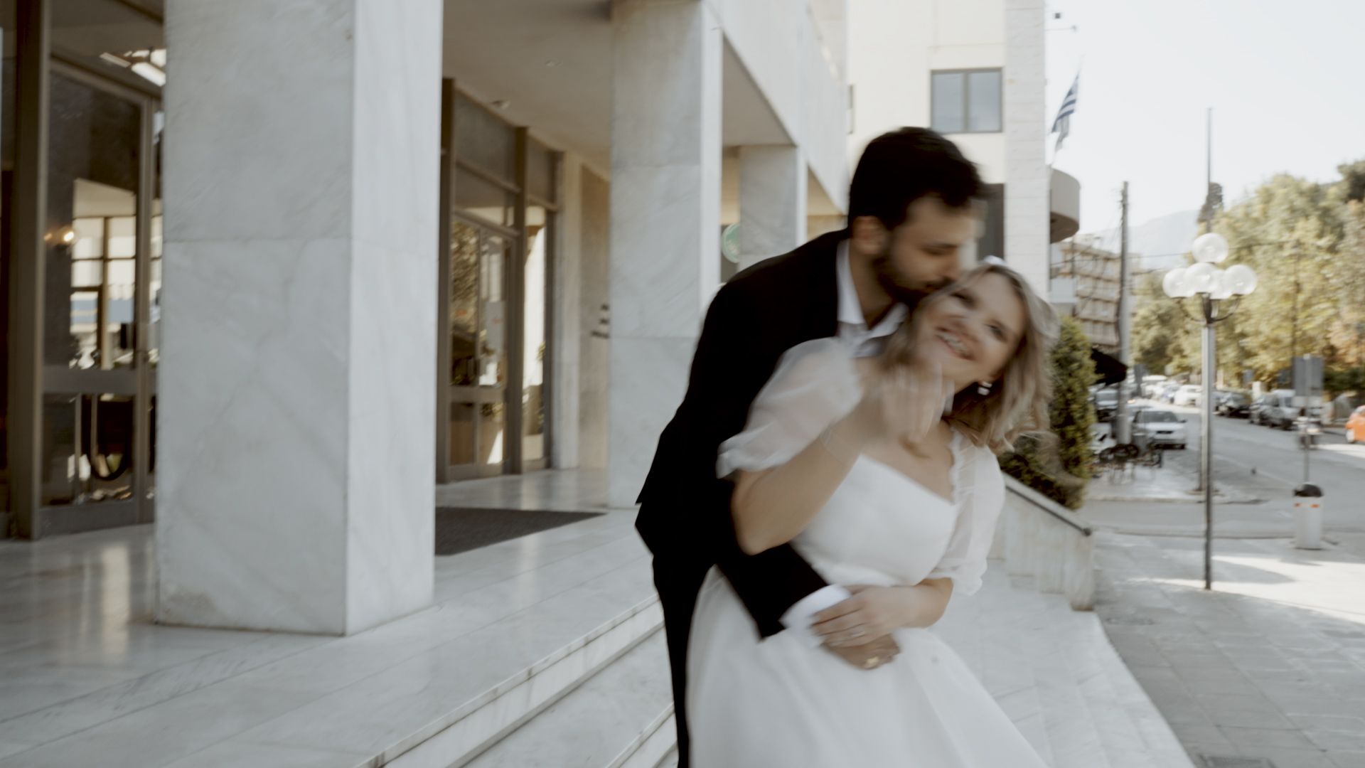 A tender moment between newlyweds outside a white stone building.