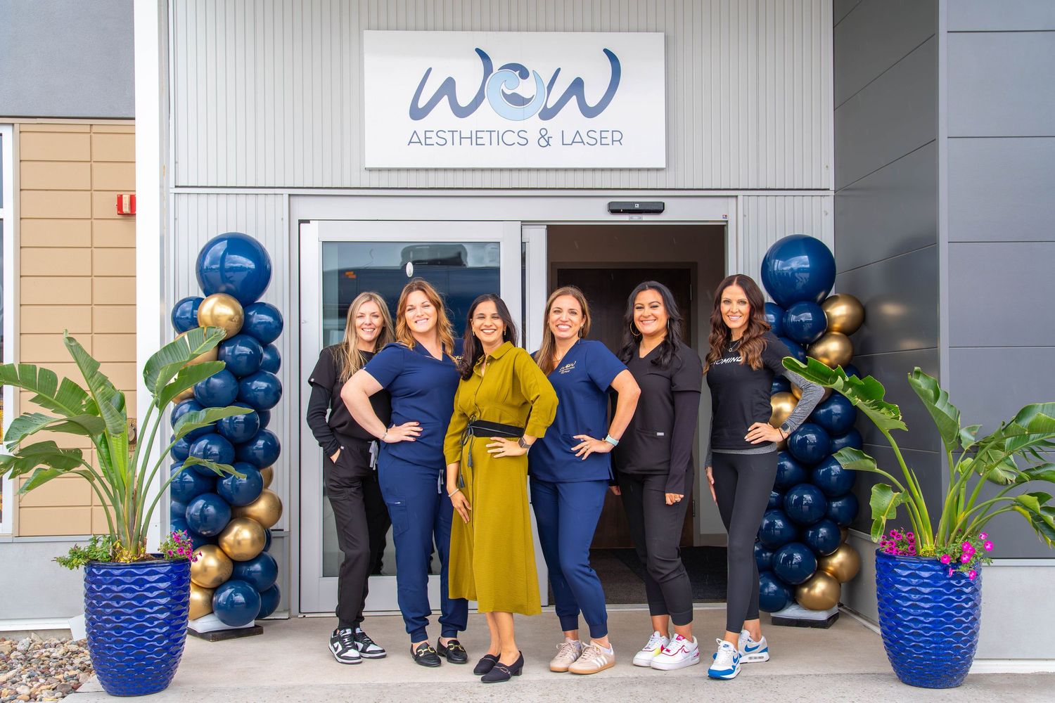 Staff members pose in front of a medical office entrance decorated with blue and gold balloon arrangements. Quad Cities Photography