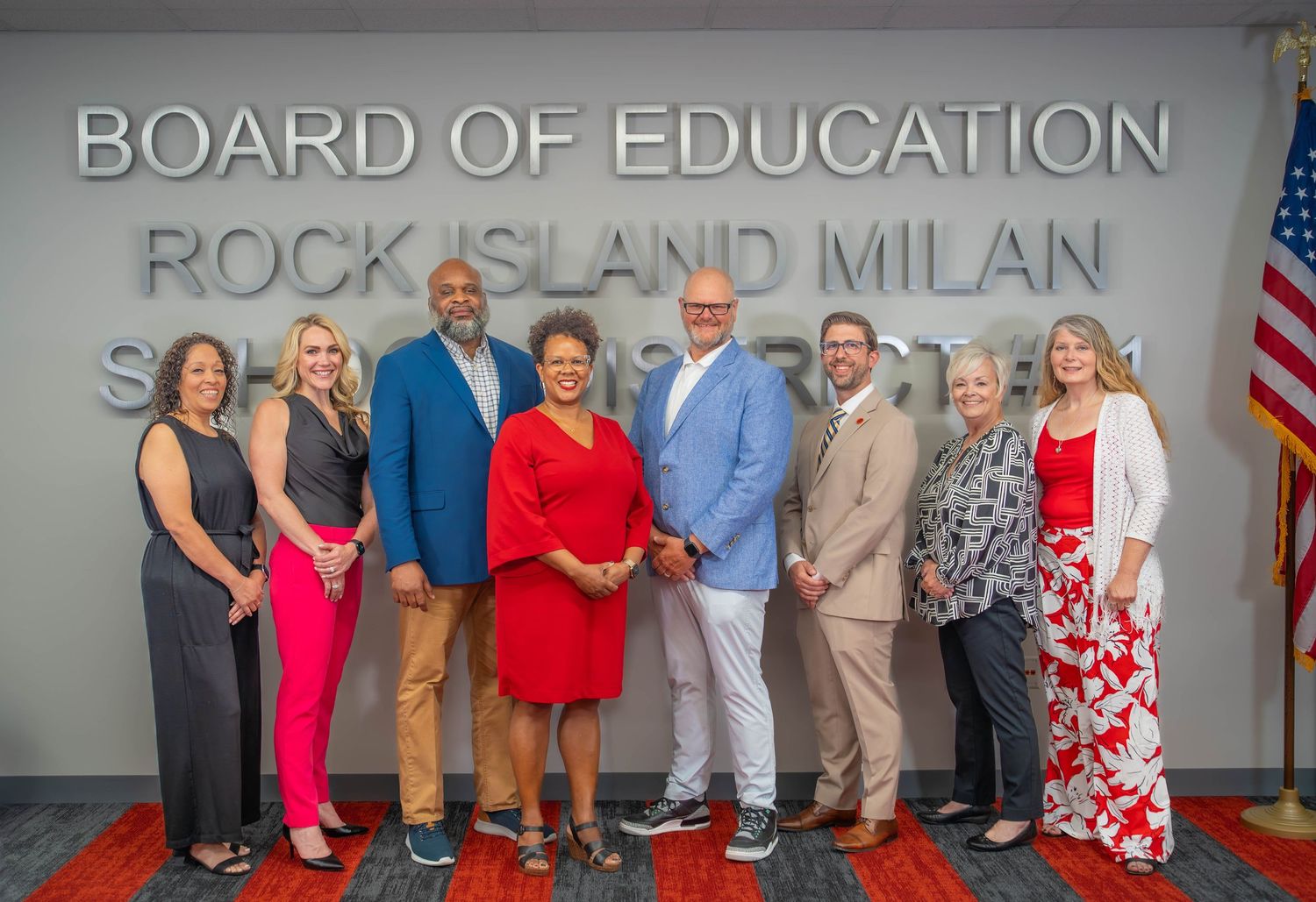Educators and administrators pose together in front of Board of Education signage for an official photo. Quad Cities Photography