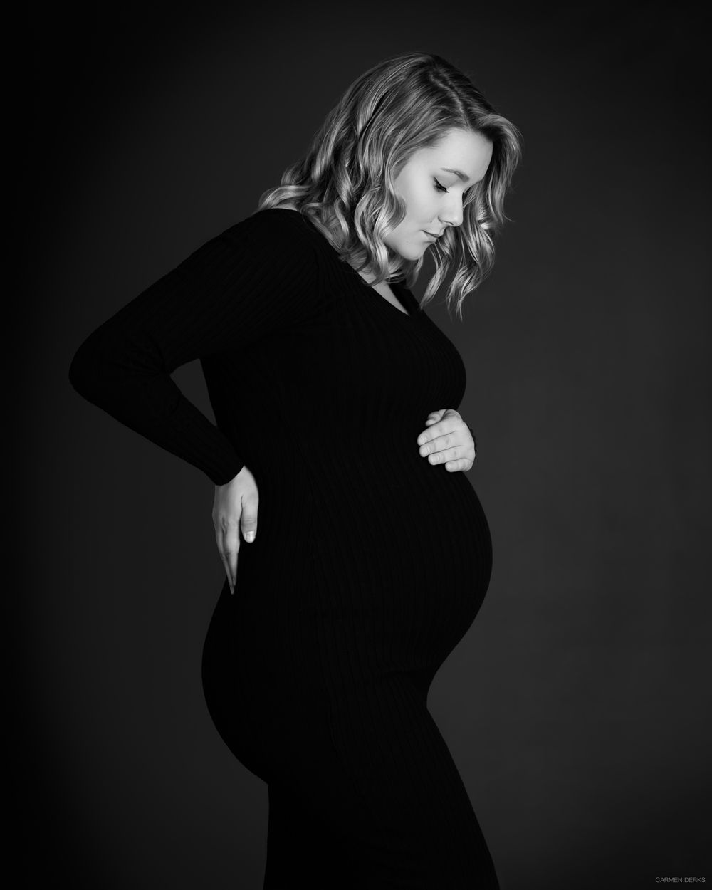 studio photoshoot tijdens zwangerschapsshoot van zwangere vrouw in zwarte strakke jurk, zwart wit foto. in beneden-leeuwen maas en waal.