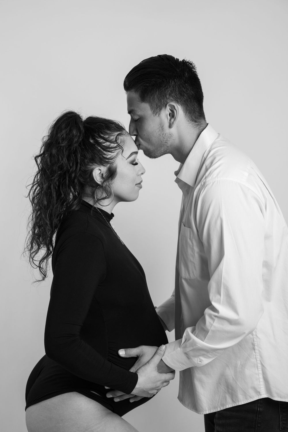 Intimate black and white maternity photo of expecting couple embracing.