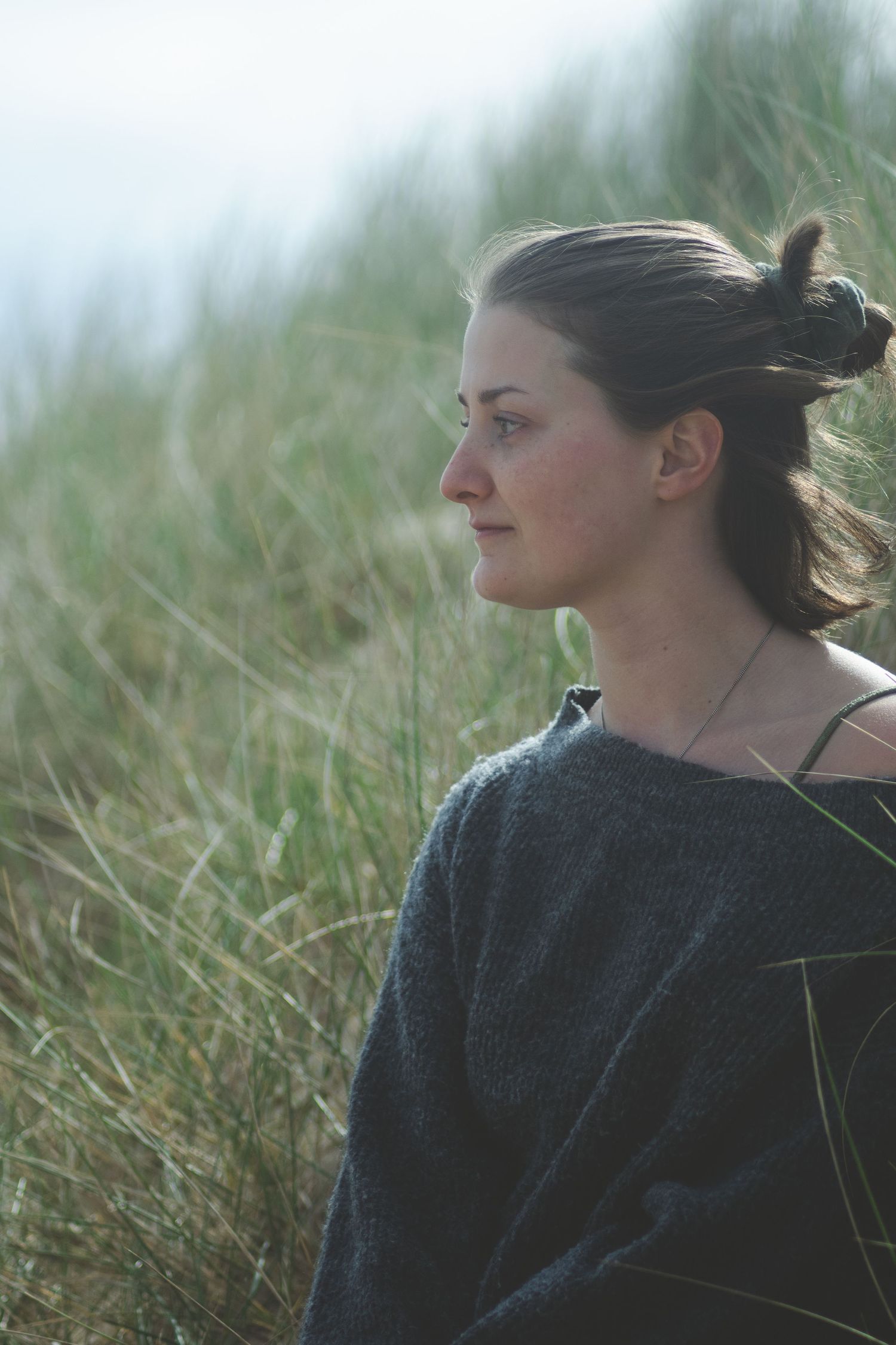 Photographie d'un portrait d'une femme assise dans une dune de sable