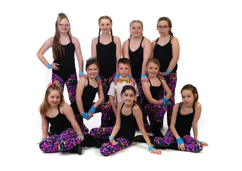 Dance team in matching black tops and patterned leggings poses for group photo.