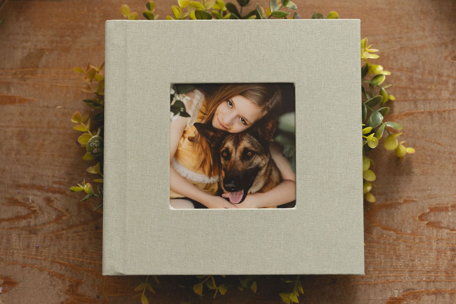 Framed photograph of two dogs nestled close together on a textured white mat, surrounded by yellow flowers.