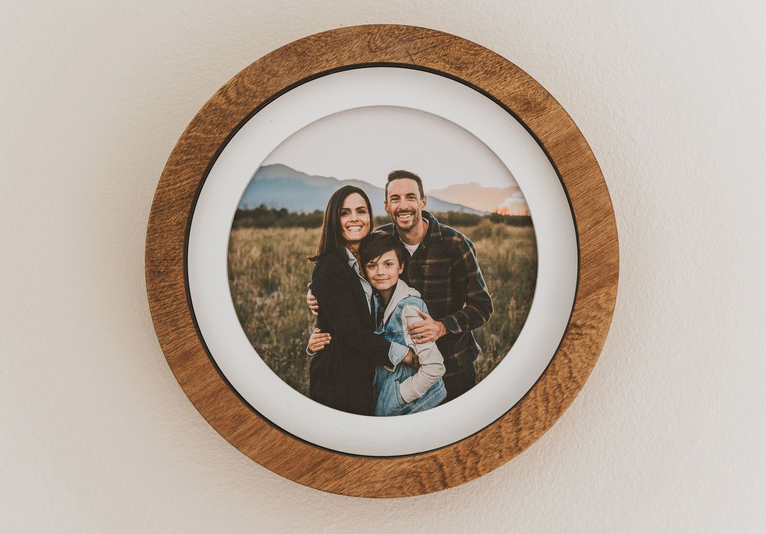 A circular framed family photograph in a wooden border mounted on a white wall.