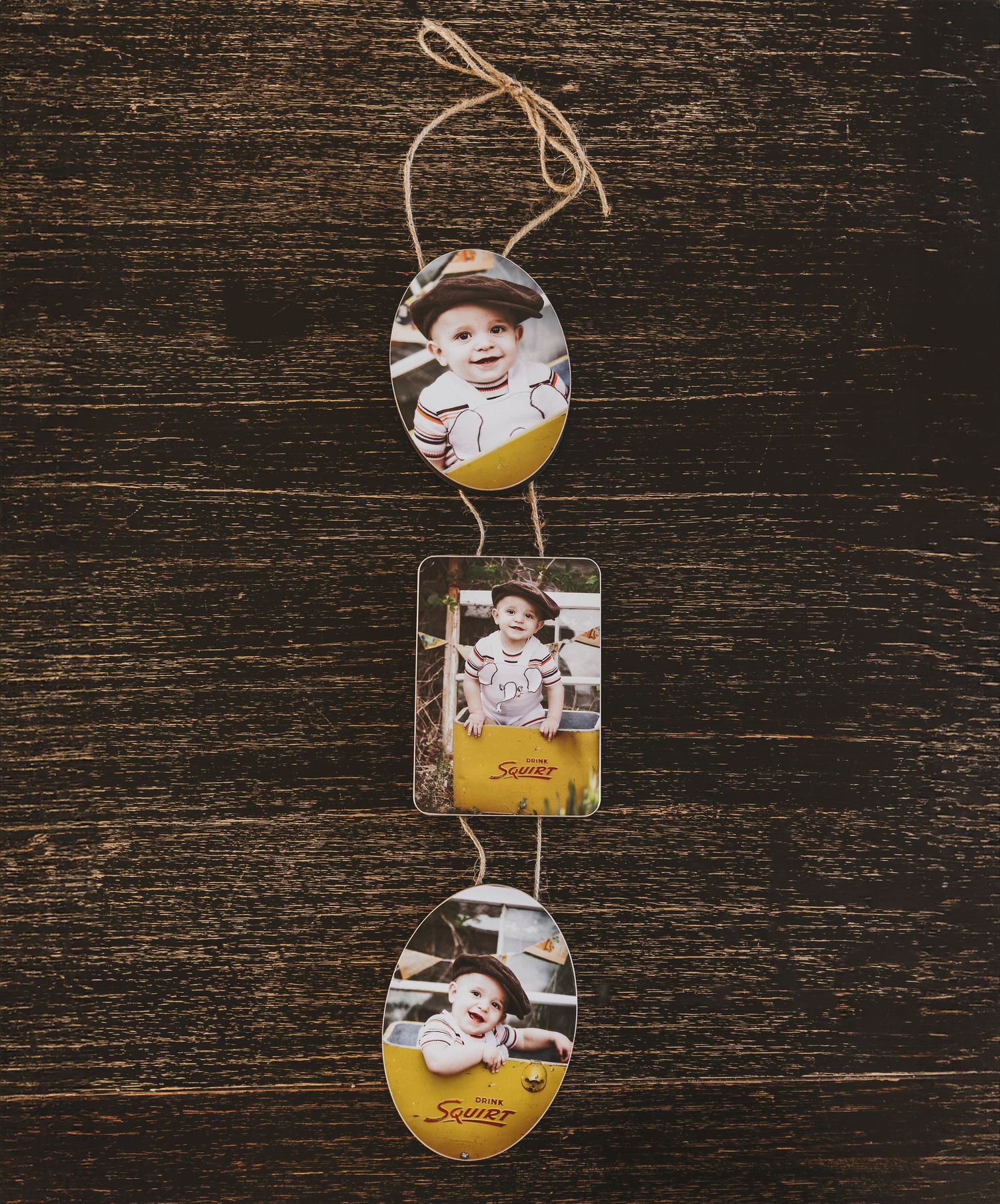 Three circular and rectangular photo ornaments with yellow accents hang vertically against a dark wooden background.