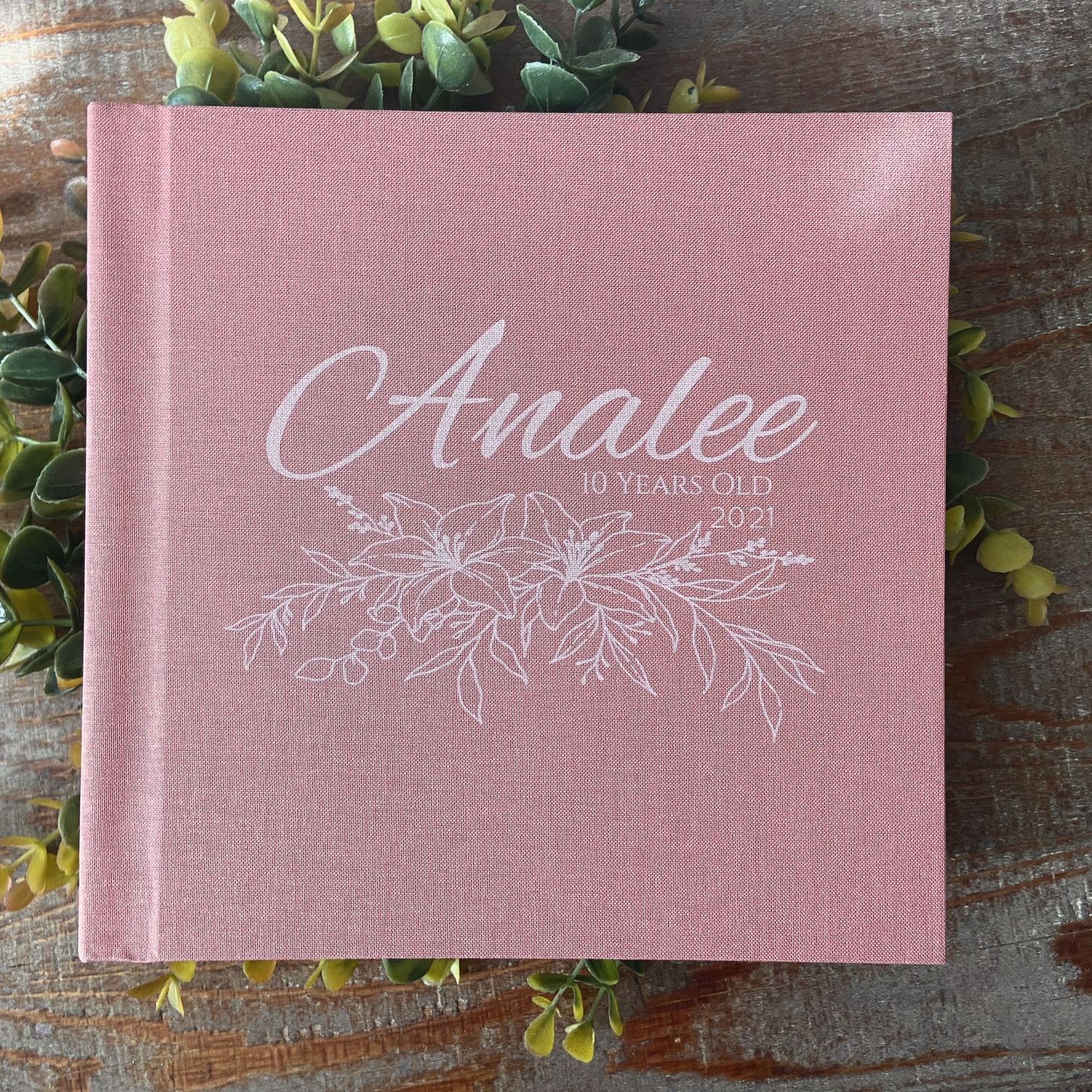 Pink linen photo album cover with elegant white floral design and cursive text reading Analee.