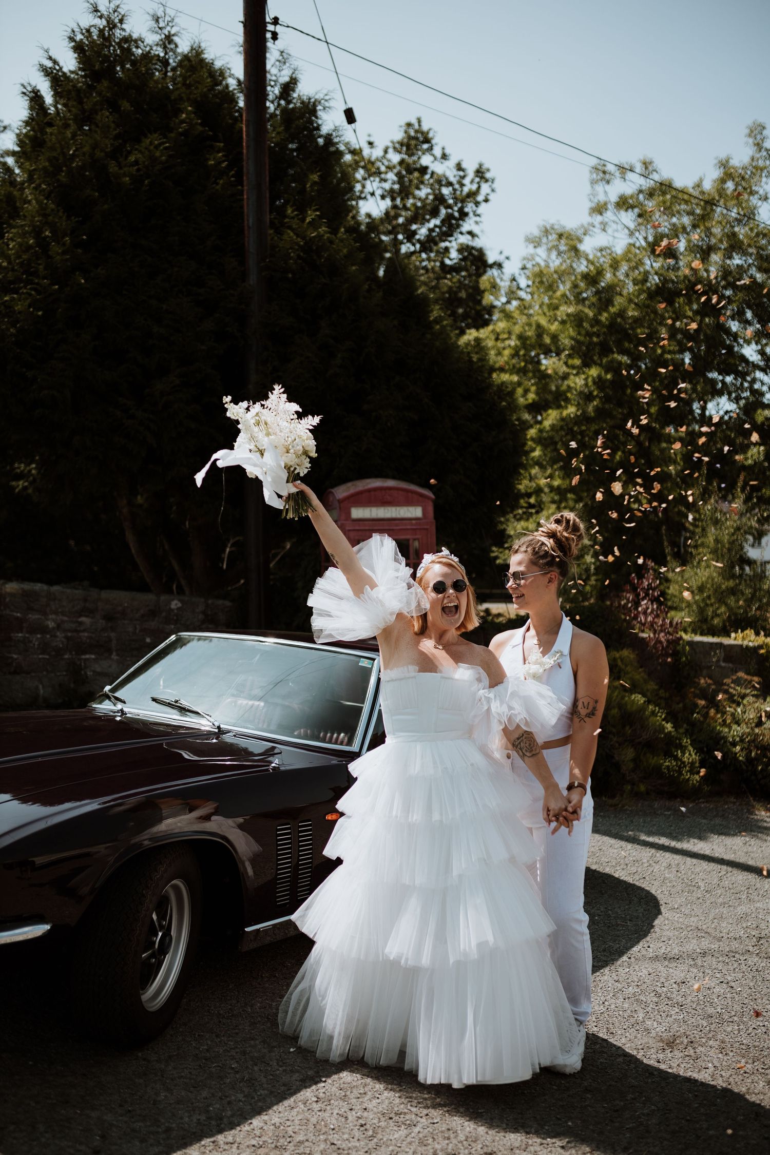 A wedding celebration by a vintage car with white dress and bouquet toss showing joyful outdoor moments.