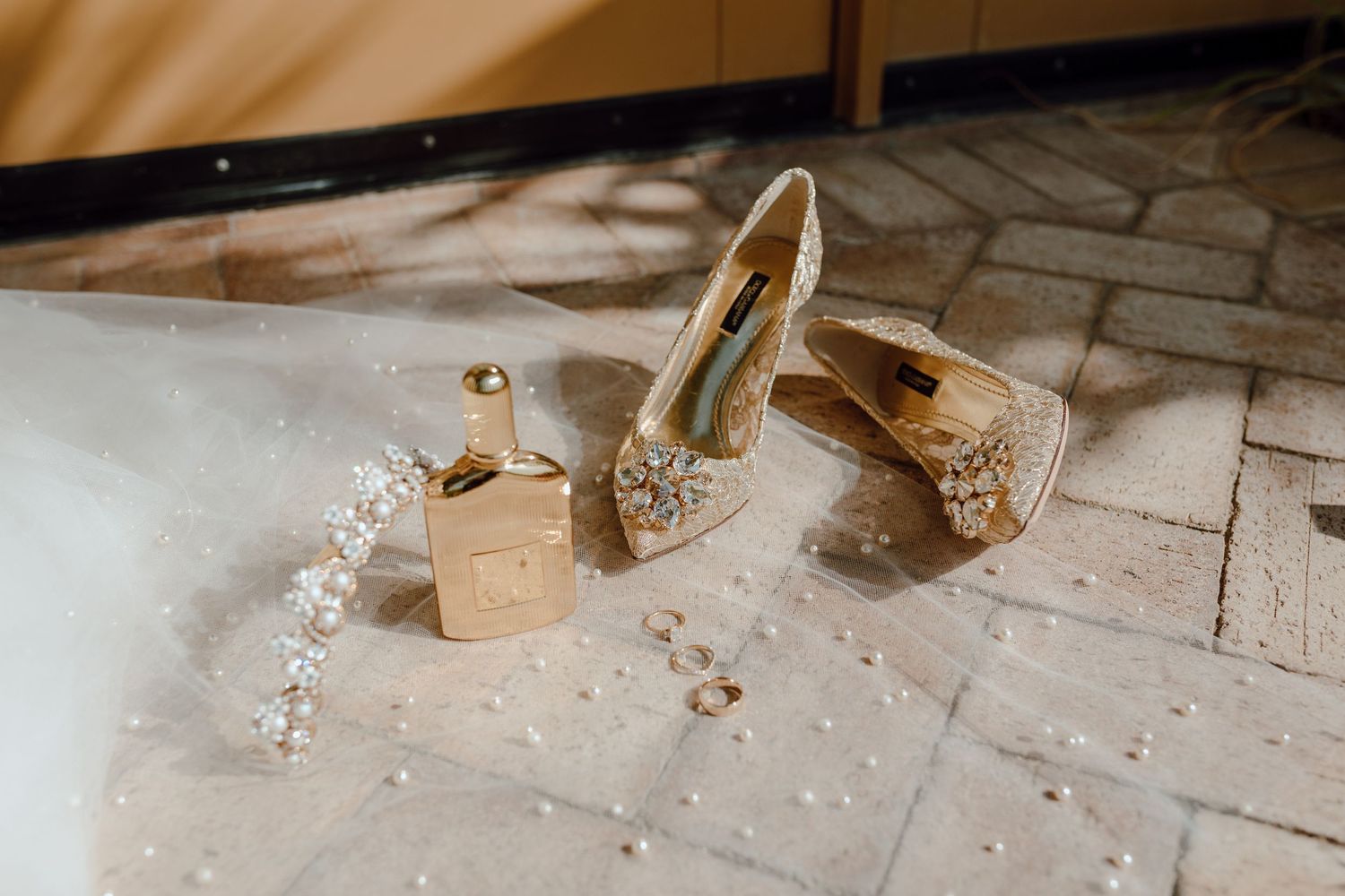 Elegant bridal shoes and jewelry arranged on a wooden floor with delicate crystal details.