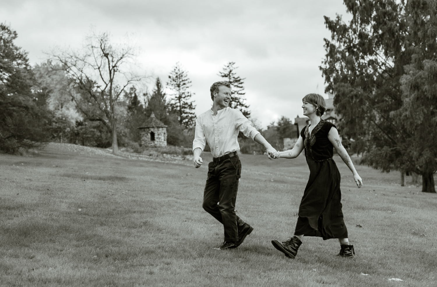 a young couple walking in a field holding hands and smiling at each other, black and white image