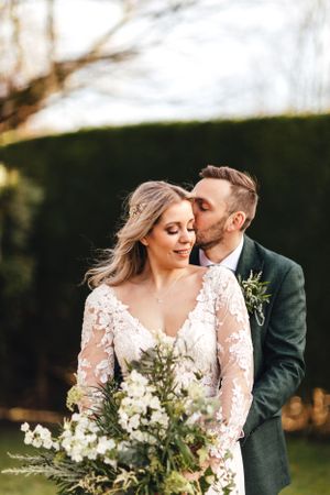 Romantic wedding moment captured with elegant lace dress and natural bouquet in garden setting.