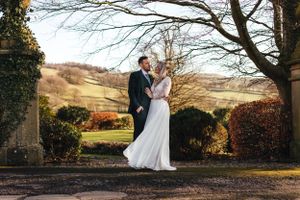 Elegant wedding couple shares a romantic moment against a backdrop of rolling hills and autumn foliage.
