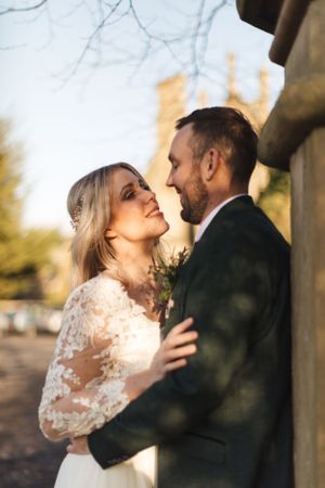 Romantic sunset wedding portrait captured against historic architecture and winter trees.