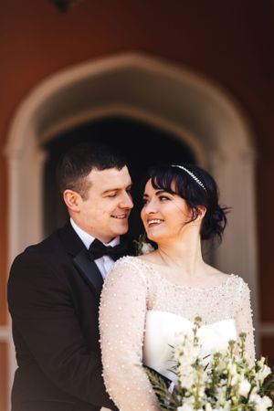 A romantic wedding portrait under an arched doorway with a bridal bouquet.