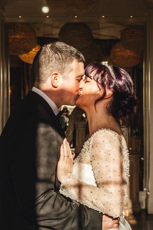 An intimate wedding kiss captured in warm indoor lighting.