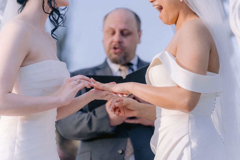 Close-up of ring exchange during wedding ceremony with officiant in background.