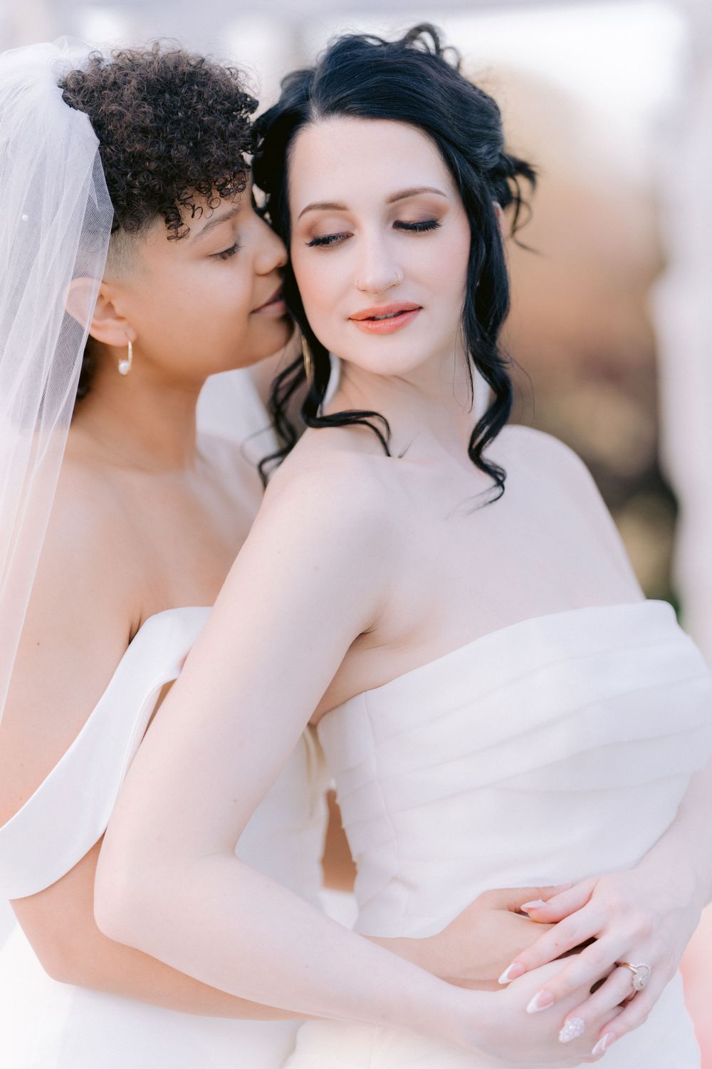 Romantic close-up portrait of two brides in white wedding dresses.