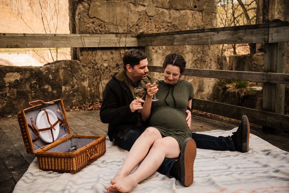 Couple enjoying a picnic with vintage basket against rustic stone wall backdrop.