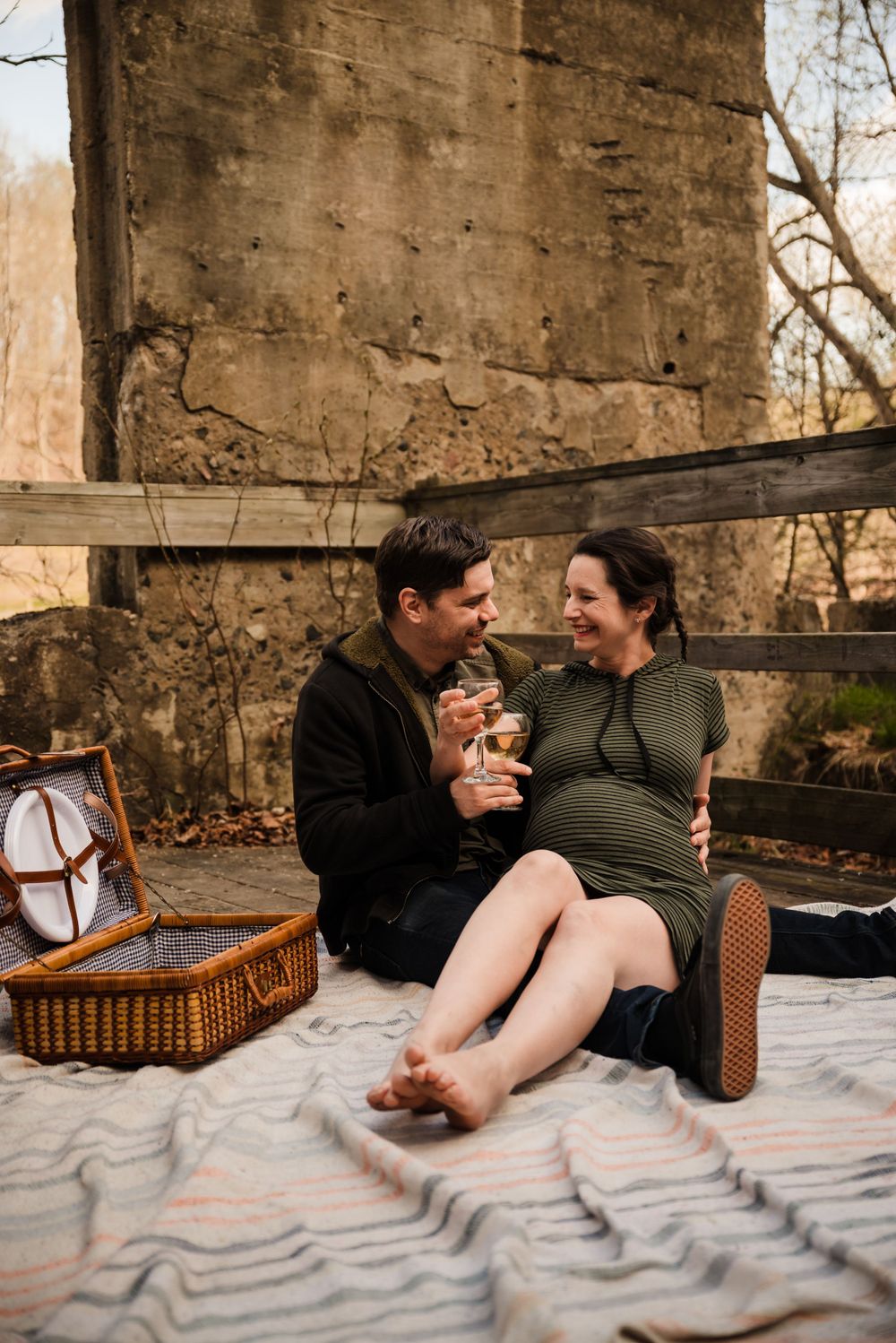 Couple sharing snacks during intimate picnic against weathered stone wall background.