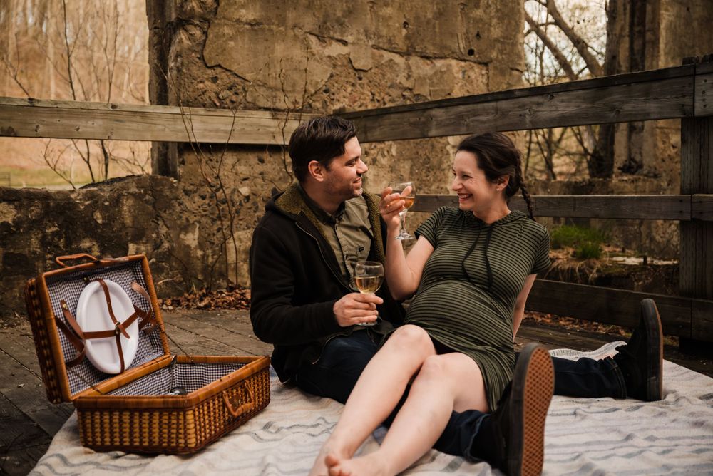 Romantic picnic scene with couple enjoying treats from wicker basket against stone ruins.