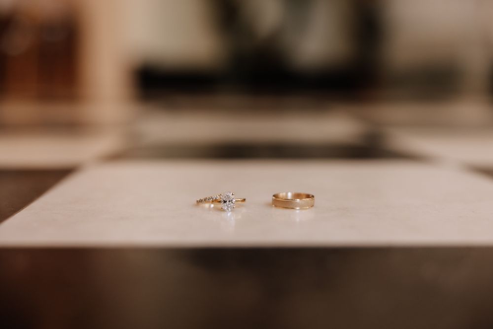 Close-up photo of gold wedding rings on a white surface with a soft blurred background.