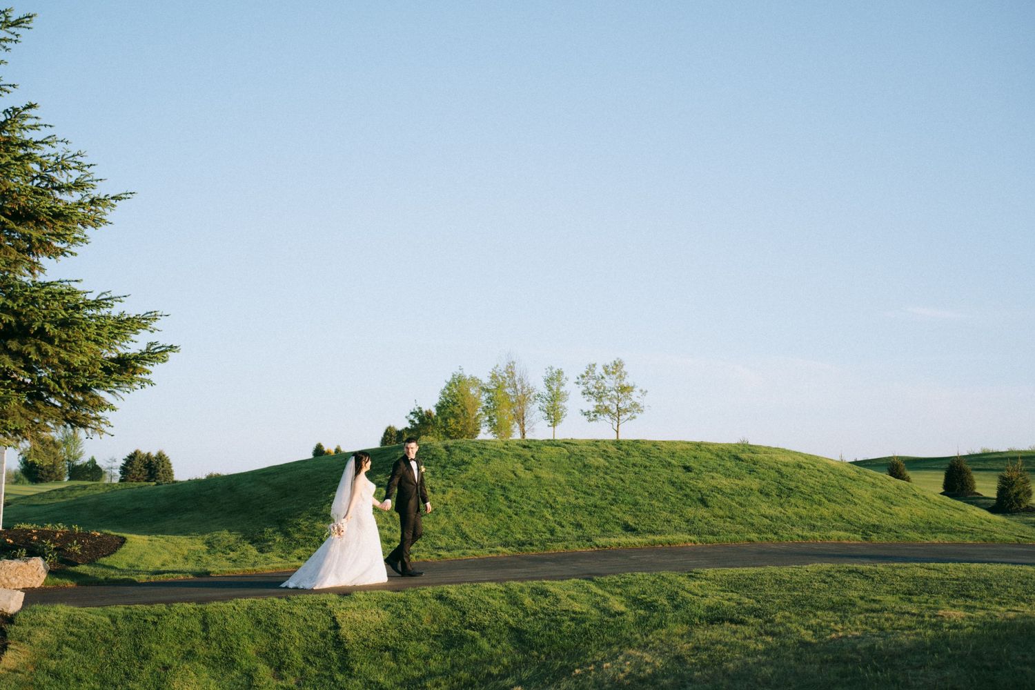 Rolling green hills and evergreen trees create a scenic backdrop for an outdoor wedding venue.