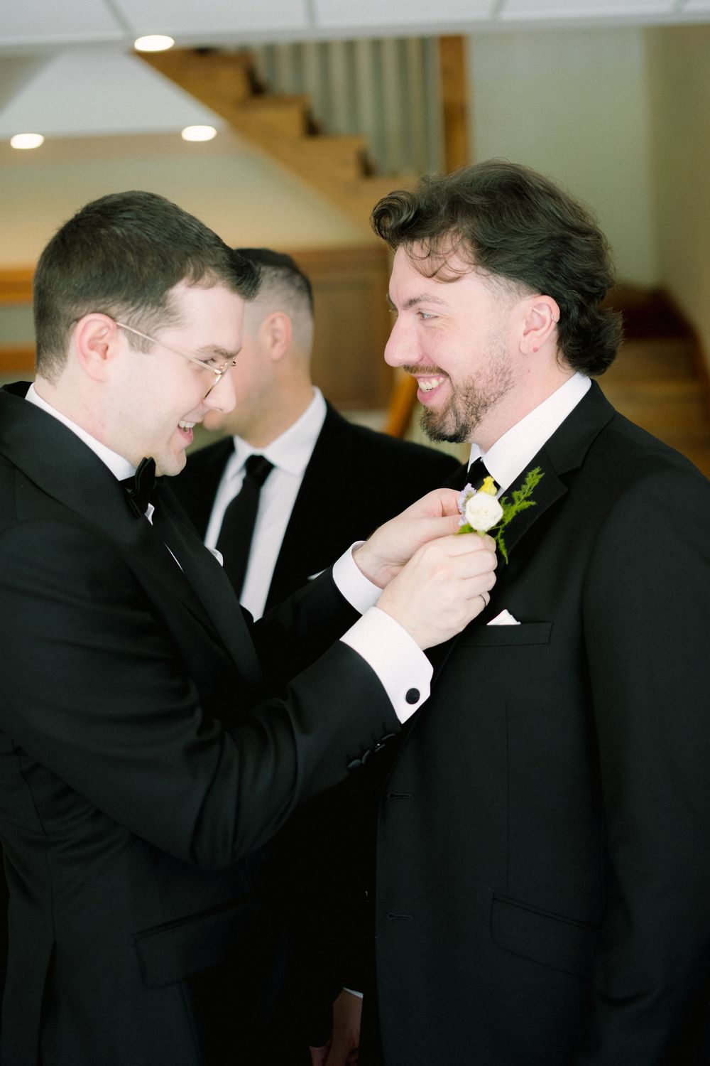 People in formal attire helping with boutonniere pinning.