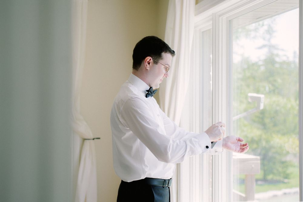Side view of person in formal wear preparing by bright window.