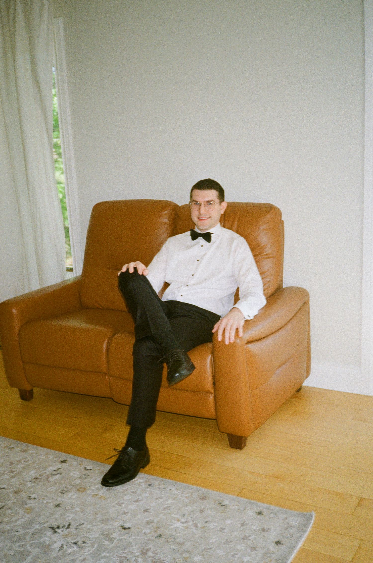 Formal attire with bow tie on leather armchair during wedding preparations.