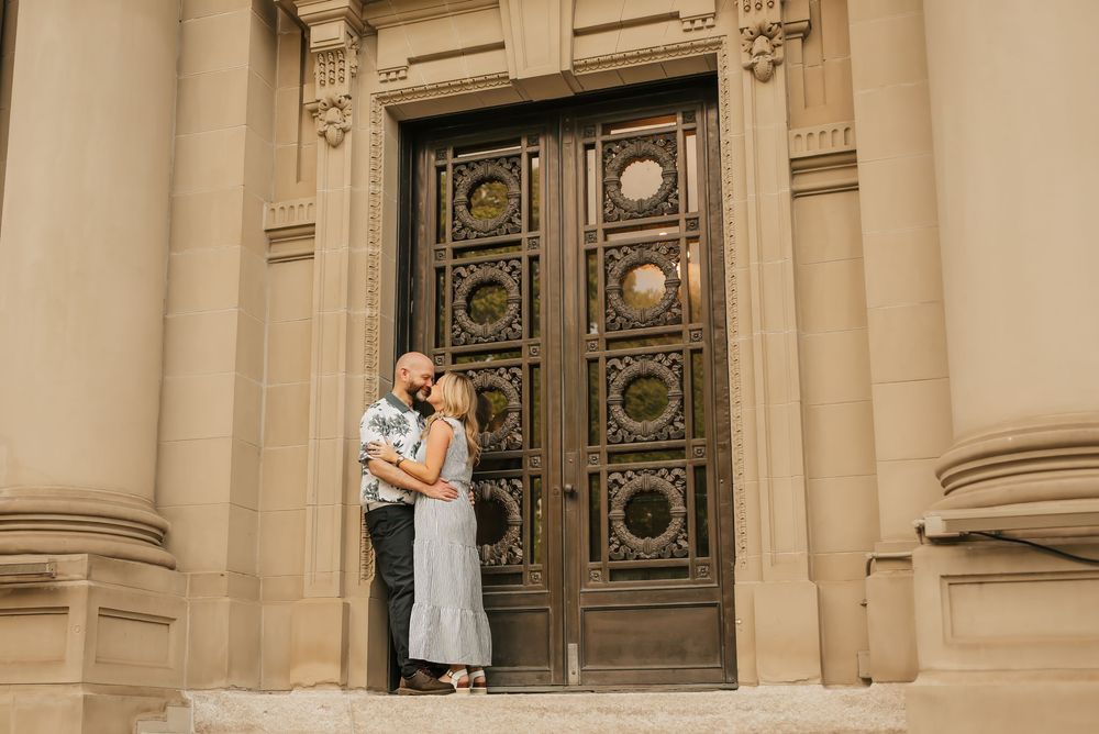 husband and wife kiss by building near Washington park in cincinnati, ohio
